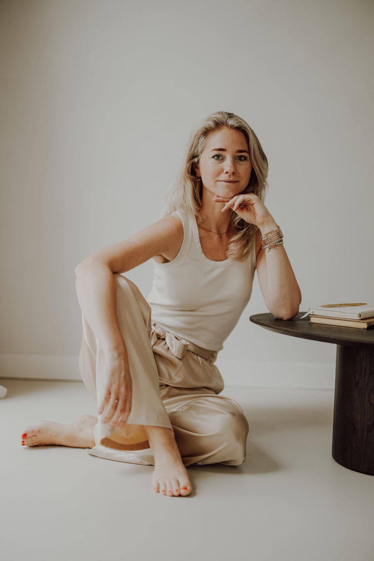 Marlien Groot Bronsvoort zit ontspannen op de vloer naast een houten tafel